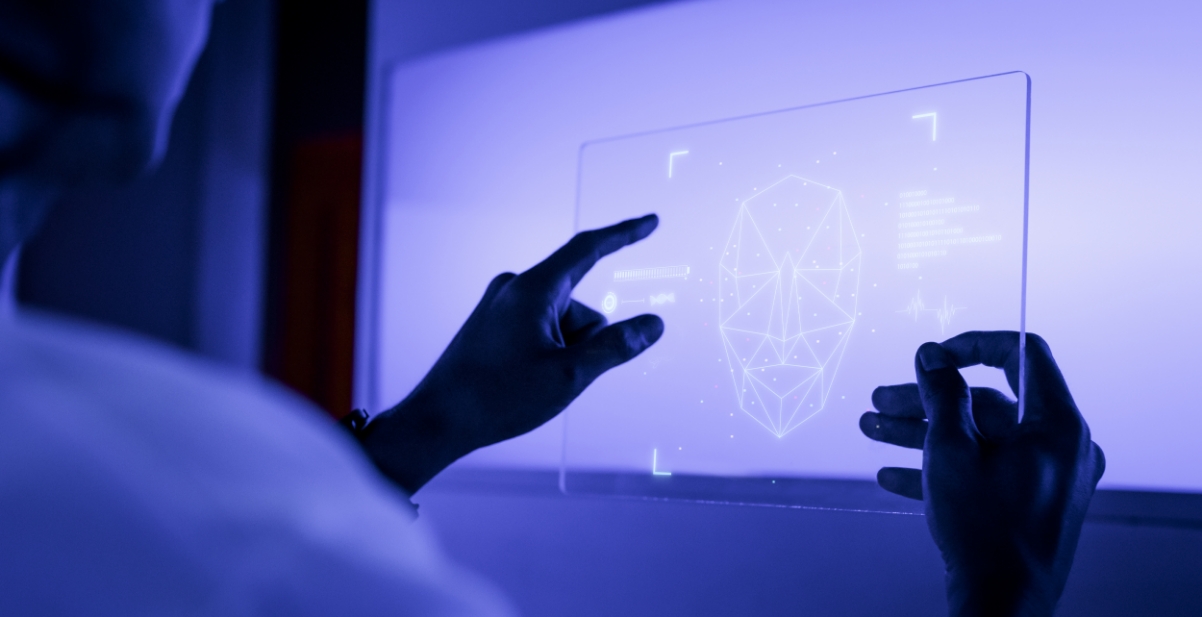 Researcher interacting with screen showing a face with data points. This is symbolic of artificial intelligence.